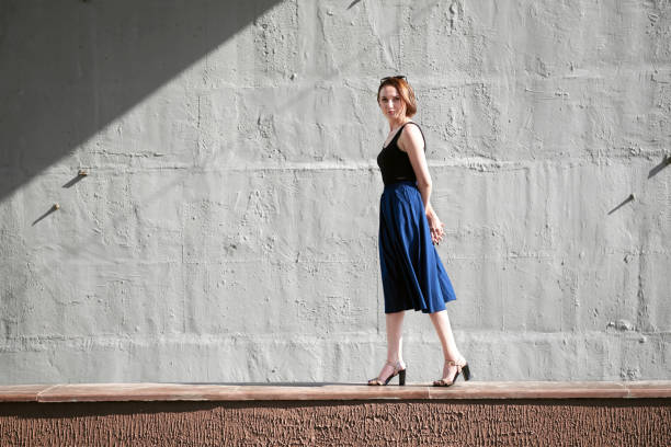 istock young girl posing against a concrete wall, dressed in black, hard light and shadows 1126948846