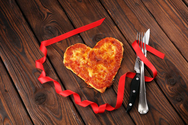 istock Valentines day pizza in heart shape on dark rustic wooden background. 1126952819