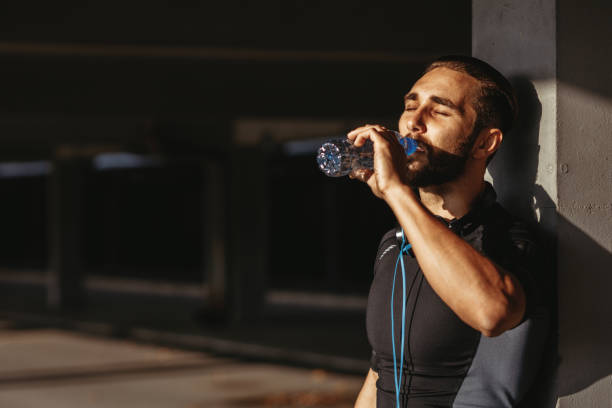 istock Young man resting and drinking water after jogging 1126952970