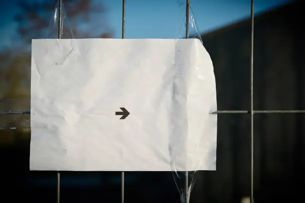 Sheet of paper with a directional arrow on a fence