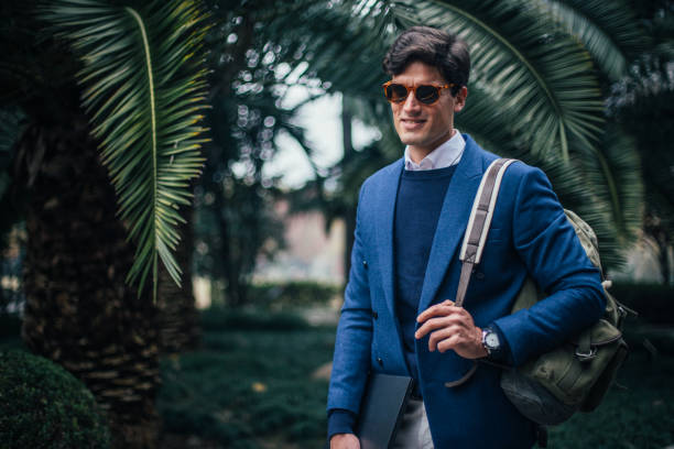 istock Man with laptop and backpack walking in the park 1126956391