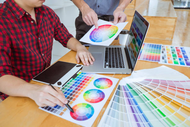 istock Teamwork of young creative designers working on project together and choose color swatch samples for selection coloring on digital graphic tablet at workspace 1126957261