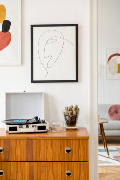 vintage et rétro intérieur de la salle de séjour avec la conception commode, enregistreur de vinyle, cactus et ses maquettes cadres affiches sur les murs blancs. chambre confortable avec parquet en bois brun et des plantes. - designer living room brown white photos et images de collection