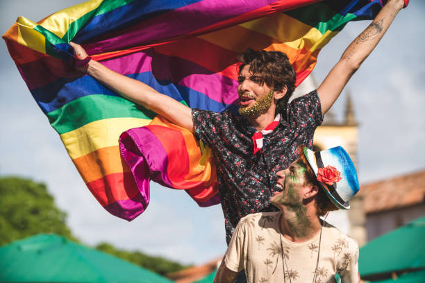 gay paar hält die lgbt flagge - homosexual gay man parade flag stock-fotos und bilder