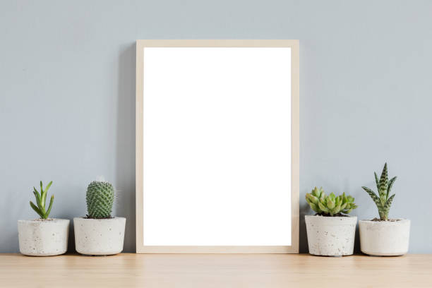 istock Botanical home interior with mock up photo frame on the brown wooden table with composition of cacti and succulents in stylish cement pots. Grey walls. Stylish and floral concept of home garden. 1126957858