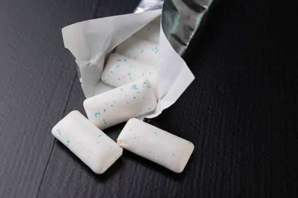 istock Chewing gum on the table. Mint refreshing tablet in a silver package. Dark background. 1126964740