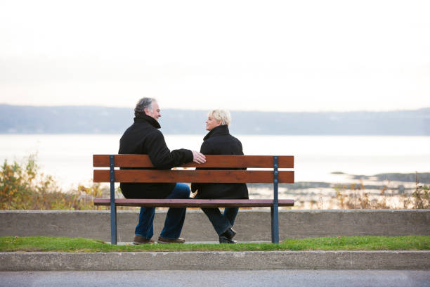 istock Mature couple sitting on bench overlooking river. 1126966976