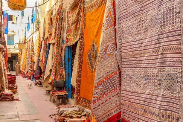 marokański bazar dywanów. kolorowe dywany na sprzedaż w wąskiej uliczce essaouira w maroku - sale zdjęcia i obrazy z banku zdjęć