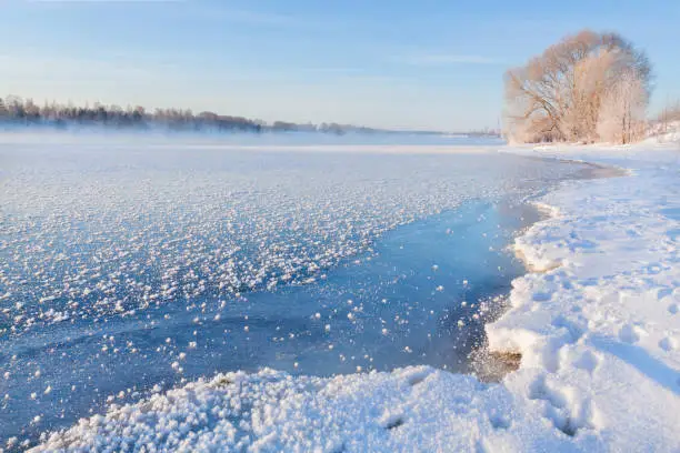 Winter landscape in the early morning overlooking the banks of the Volga River. Frosty fog obscures the banks of the river. The tops of the trees are covered with hoarfrost.