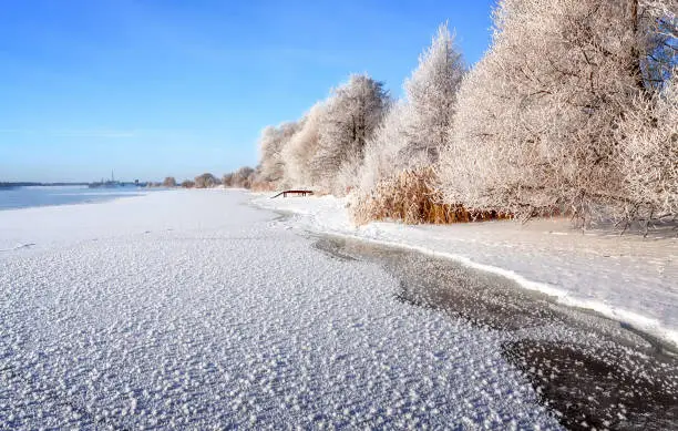 Winter landscape on a clear frosty day overlooking the banks of the Volga River. Frosty fog obscures the banks of the river.The tops of the trees are covered with hoarfrost.