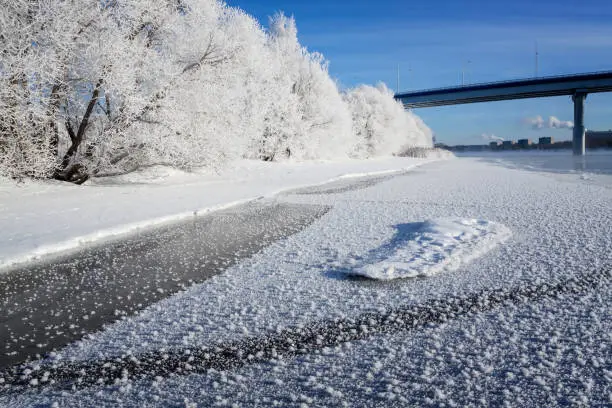 Winter landscape in the early morning overlooking the city of Dubna and the bridge over the Volga. Frosty fog obscures the banks of the river. The tops of the trees are covered with hoarfrost.