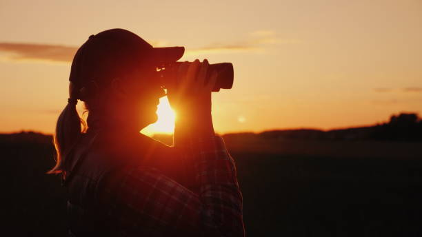 A woman looking through binoculars at sunset. Travel and safari concept stock photo