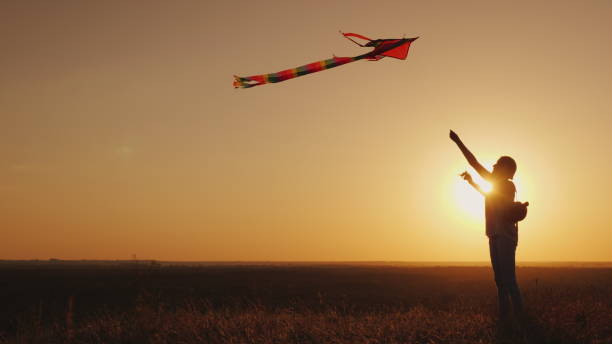 istock Woman With a children's backpack behind her back runs a kite at sunset. Dream and return to childhood concept 1126974435