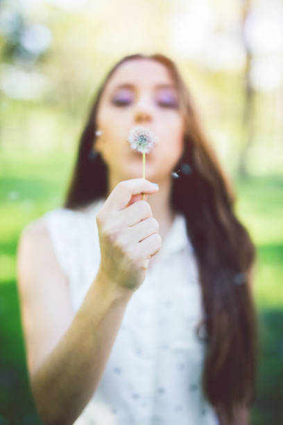 istock Brunette girl blowing on a dandelion 1126974716