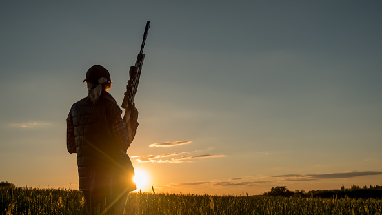 Tiro deportivo y caza-mujer con un rifle al atardecer photo