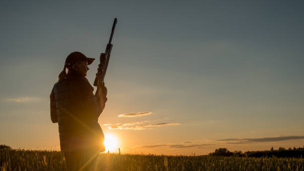 Sport shooting and hunting - woman with a rifle at sunset Beautiful silhouette of a woman with a rifle in the rays of the setting sun. Sports shooting and hunting concept. 4K video female sharp shooter stock pictures, royalty-free photos & images