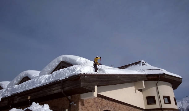 istock Worker removes snow from the roof at Rosa Khutor 1126975486