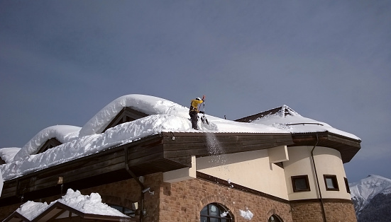 Dangerous icicles hang from roof of the house. Big icicles in the streets of the winter town. Winter time