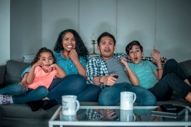 istock Family sitting on sofa and watching TV together 1126976031