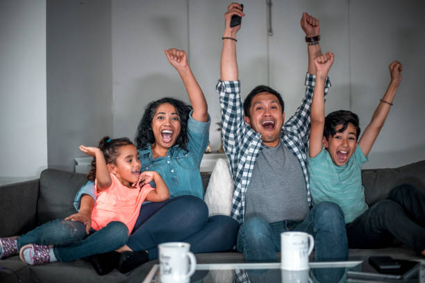 istock Family cheering while watching TV at home 1126976033