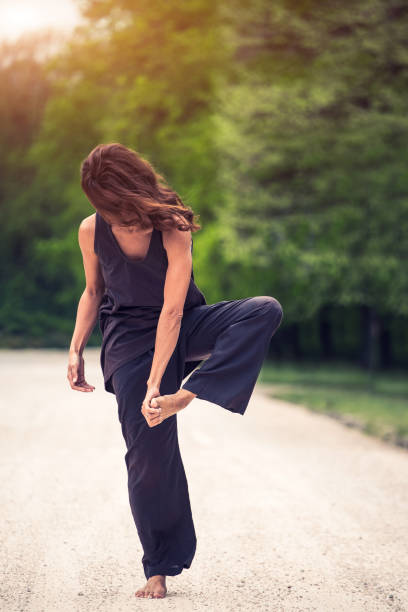 istock attractive woman practicing yoga in park 1126978888