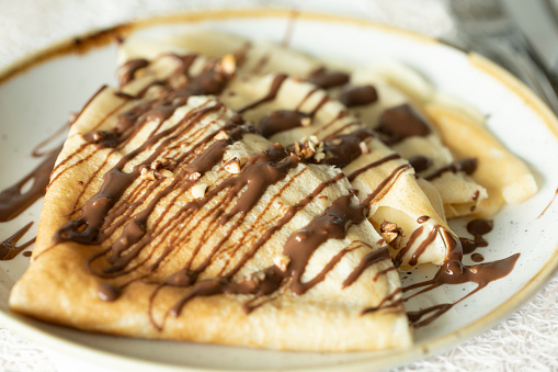 Three crepes with drizzle chocolate, hazelnut spread, sprinkles of nuts