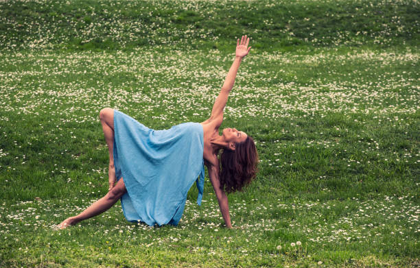 istock beautiful woman doing yoga on meadow 1126981310
