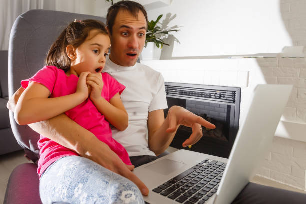 istock Man with daughter looking at internet on laptop 1126982725