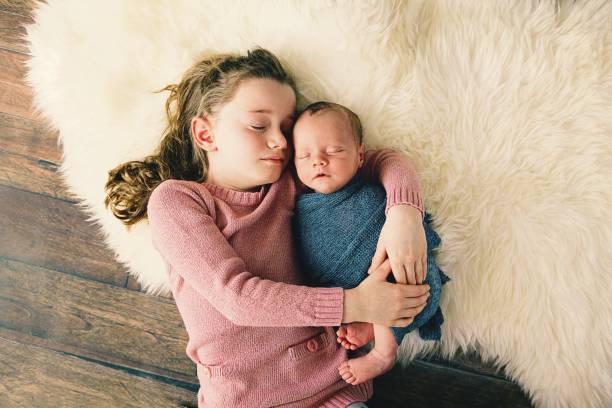 kleine mädchen umarmt neugeborenen bruder - fake fur white happiness beginnings stock-fotos und bilder