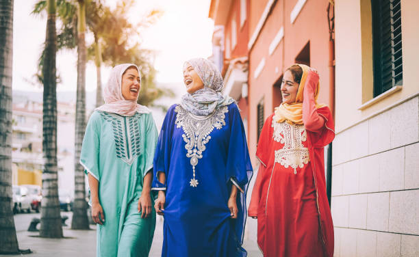 szczęśliwe muzułmańskie kobiety chodzące po centrum miasta - arabskie młode dziewczyny bawiące się spędzając czas i śmiejąc się razem na świeżym powietrzu - pojęcie ludzi, kultury i religii - women street dress city zdjęcia i obrazy z banku zdjęć