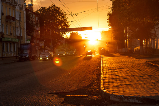 sunset on the city street with pedestrians and cars
