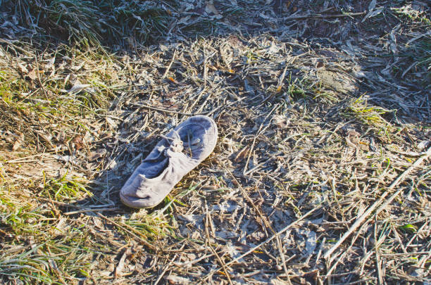 A view of a little lost white shoe on the ground in the park under the frozen and cold winter season.