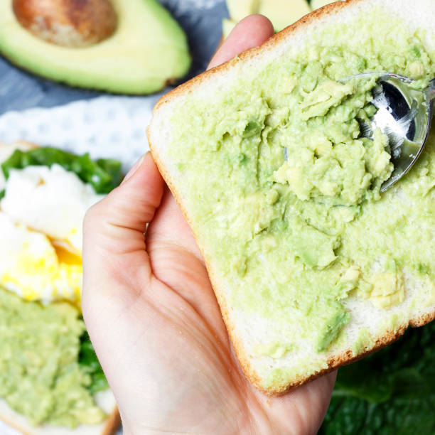 Female hands making avocado sandwich, top view