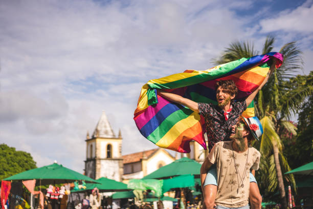 гей-пара, держащая флаг лгбт - gay pride стоковые фото и изображения