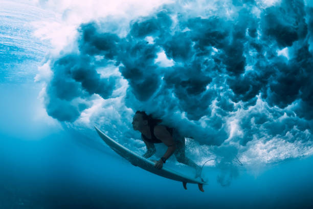 istock Surfer girl with surfboard dive underwater with under ocean wave with foam. 1127028657