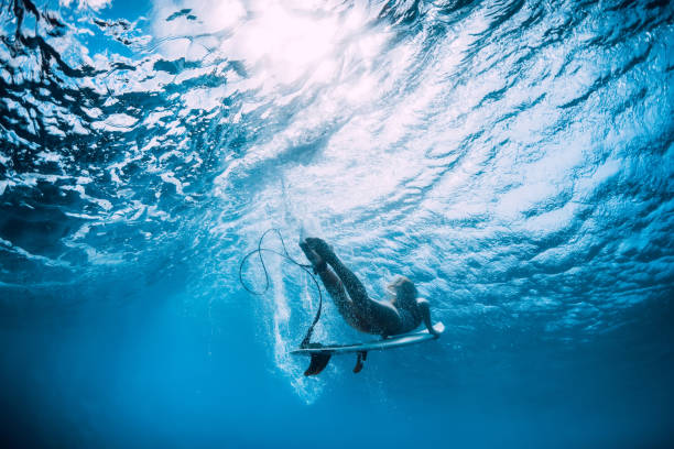 istock Surfer girl with surfboard dive underwater under ocean wave. 1127028685