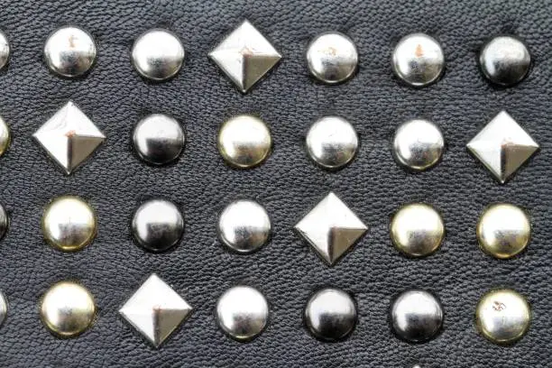 Metal studs on black leather background. Heavy metal background.