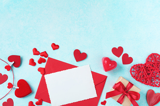 Valentines day background. Envelope, greeting card, gift box and red hearts for holiday message top view.