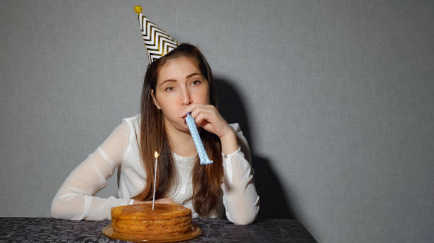 一人で悲しい女の子を祝う休日、彼はケーキや、キャンドルでテーブルで一人で座っています。 - cake birthday candle blowing ストックフォトと画像