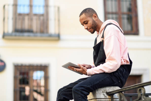 istock Young black man using digital tablet in urban background. 1127056490