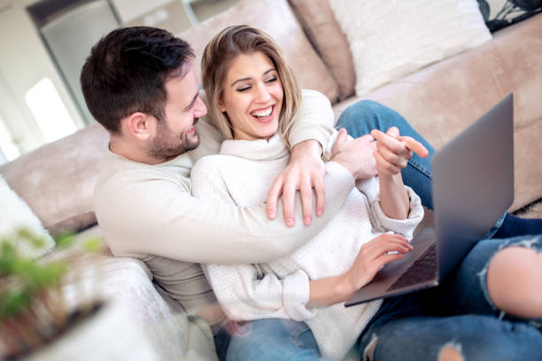 istock Young couple relaxing on sofa with laptop 1127060603