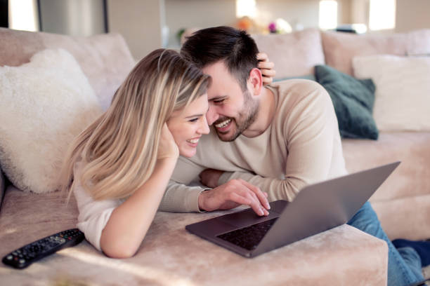 istock Young couple relaxing on sofa with laptop 1127060642