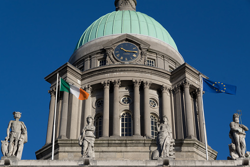 Dublin, Ireland - February 2, 2019:  The dome of the Custom House, a neoclassical styled public building in the centre of Dublin, on the banks of the River Liffey.  Originally constructed in 1791, it was built to the design of James Gandon.  Its purpose was to house government excise officers, policing trade arriving and departing from Dublin Port.  It was decorated by sculptures by Edward Smyth.  The statues on the pediment are of Mercury, Plenty, Industry  (with a bee-hive) and Neptune, representing together 'Plenty and Industry'. In 1921 it was burnt down by the Irish Republican Army and then rebuilt in 1928, once Ireland secured independence from Britain.  Today it houses Ireland's Department of Housing, Planning and Local Government.