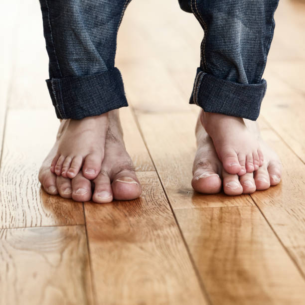 niño de pie descalzo en los pies de su padre - child human foot barefoot jeans fotografías e imágenes de stock