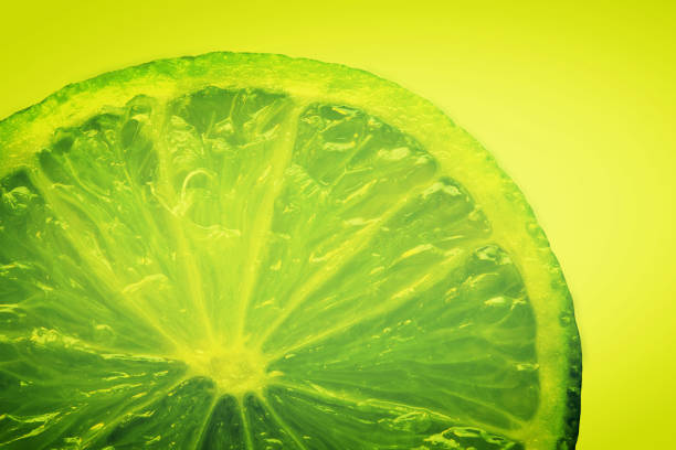 One whole and one sliced lime on a wooden background with reflection. Studio shot.
