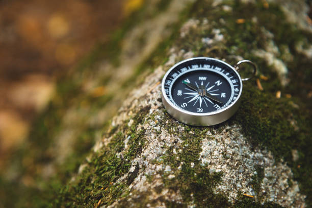istock Magnetic compass with a black dial on a wild stone covered with green moss. The concept of finding the way and navigation 1127069528