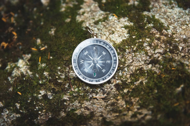 istock Magnetic compass with a black dial on a wild stone covered with green moss. The concept of finding the way and navigation 1127070432