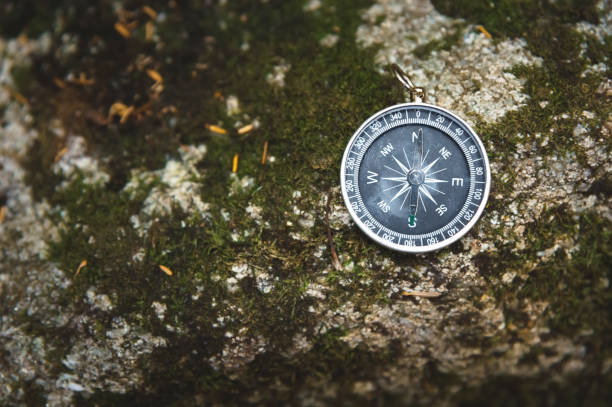 istock Magnetic compass with a black dial on a wild stone covered with green moss. The concept of finding the way and navigation 1127070445