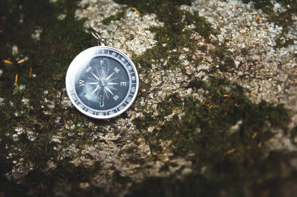 istock Magnetic compass with a black dial on a wild stone covered with green moss. The concept of finding the way and navigation 1127070632