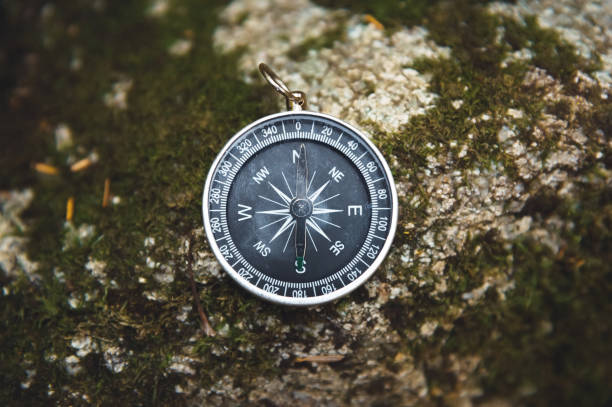 istock Magnetic compass with a black dial on a wild stone covered with green moss. The concept of finding the way and navigation 1127070655